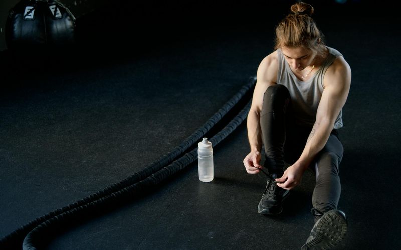 Athletic shoes and water bottle on a dark floor